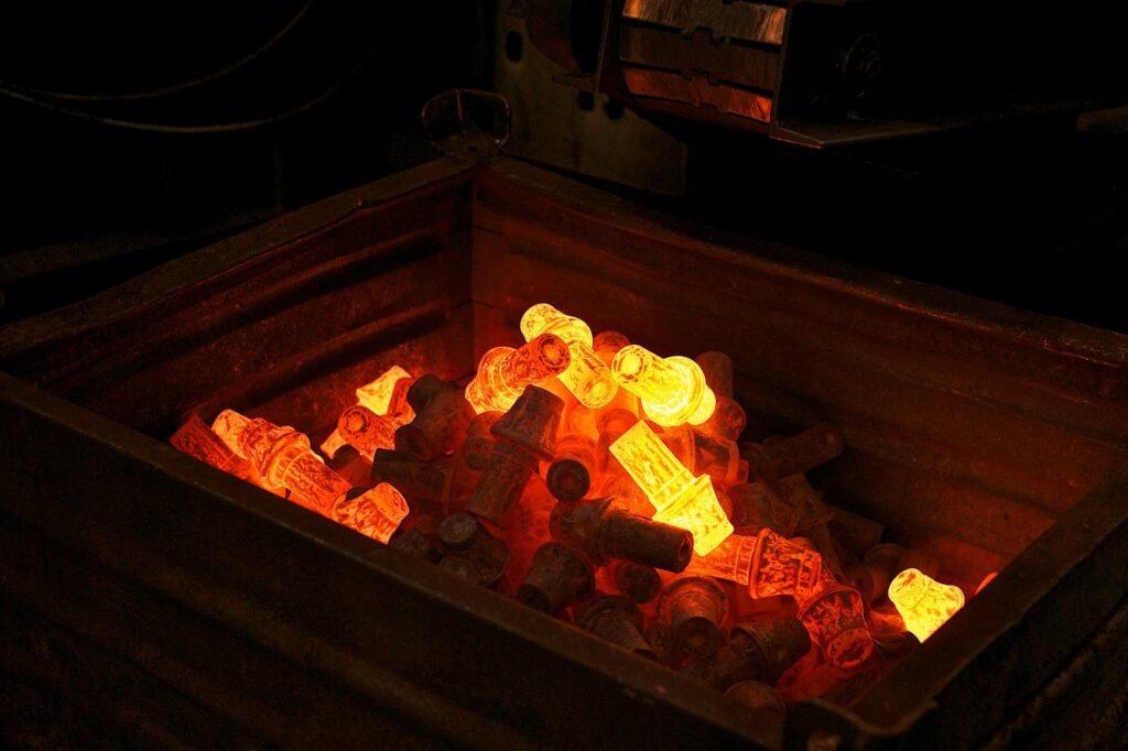 Glühende Stahlformteile in Metallbehälter